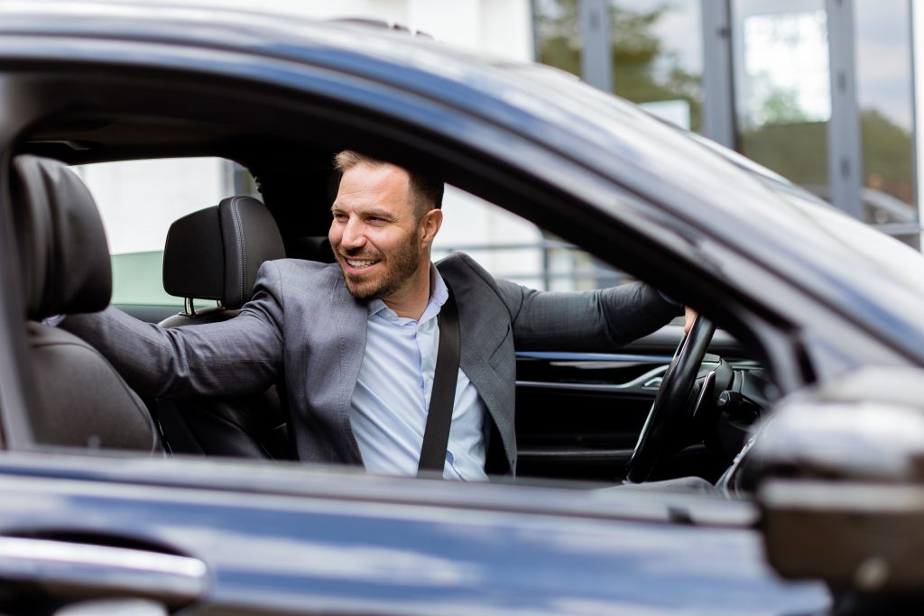 Welcoming smile from a joyful driver in a luxury sedan on a sunny day