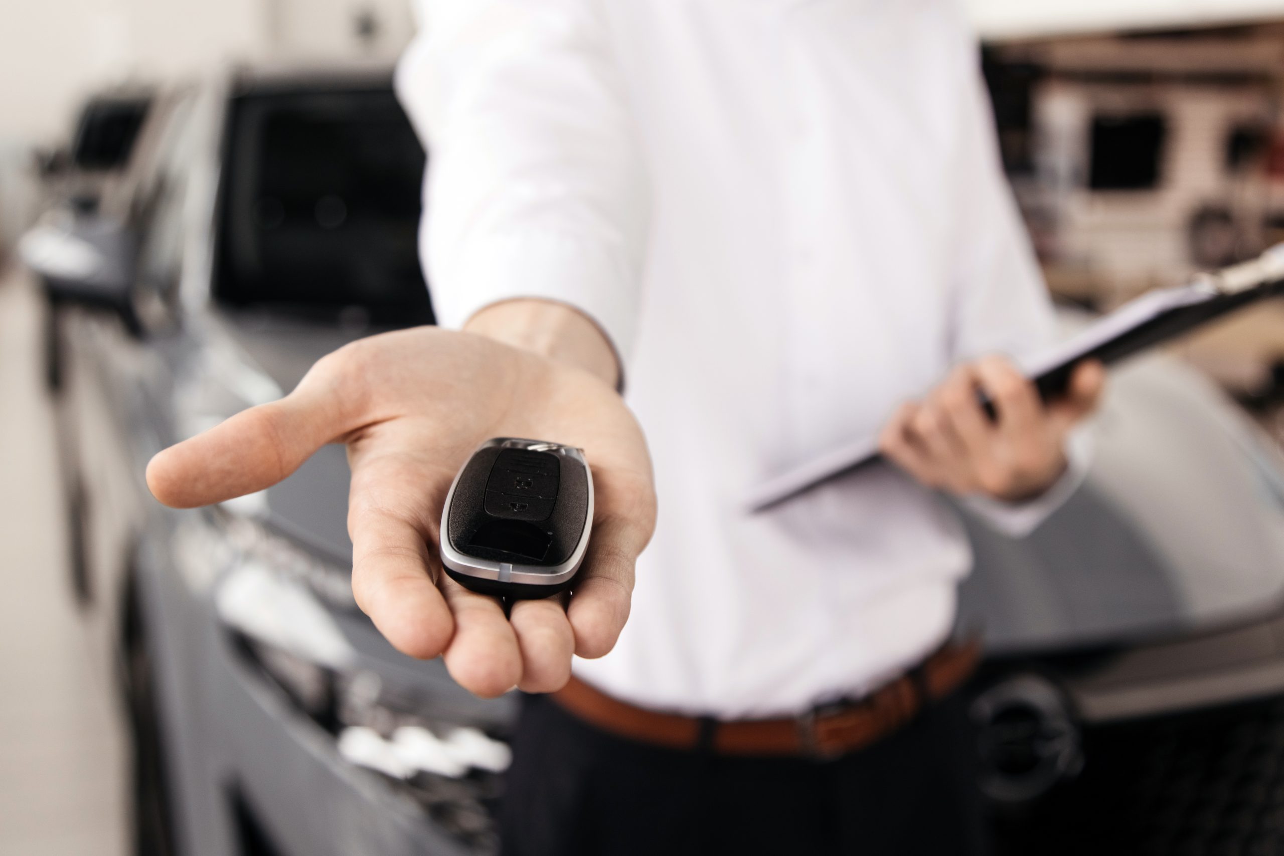 The car dealer hands the car keys